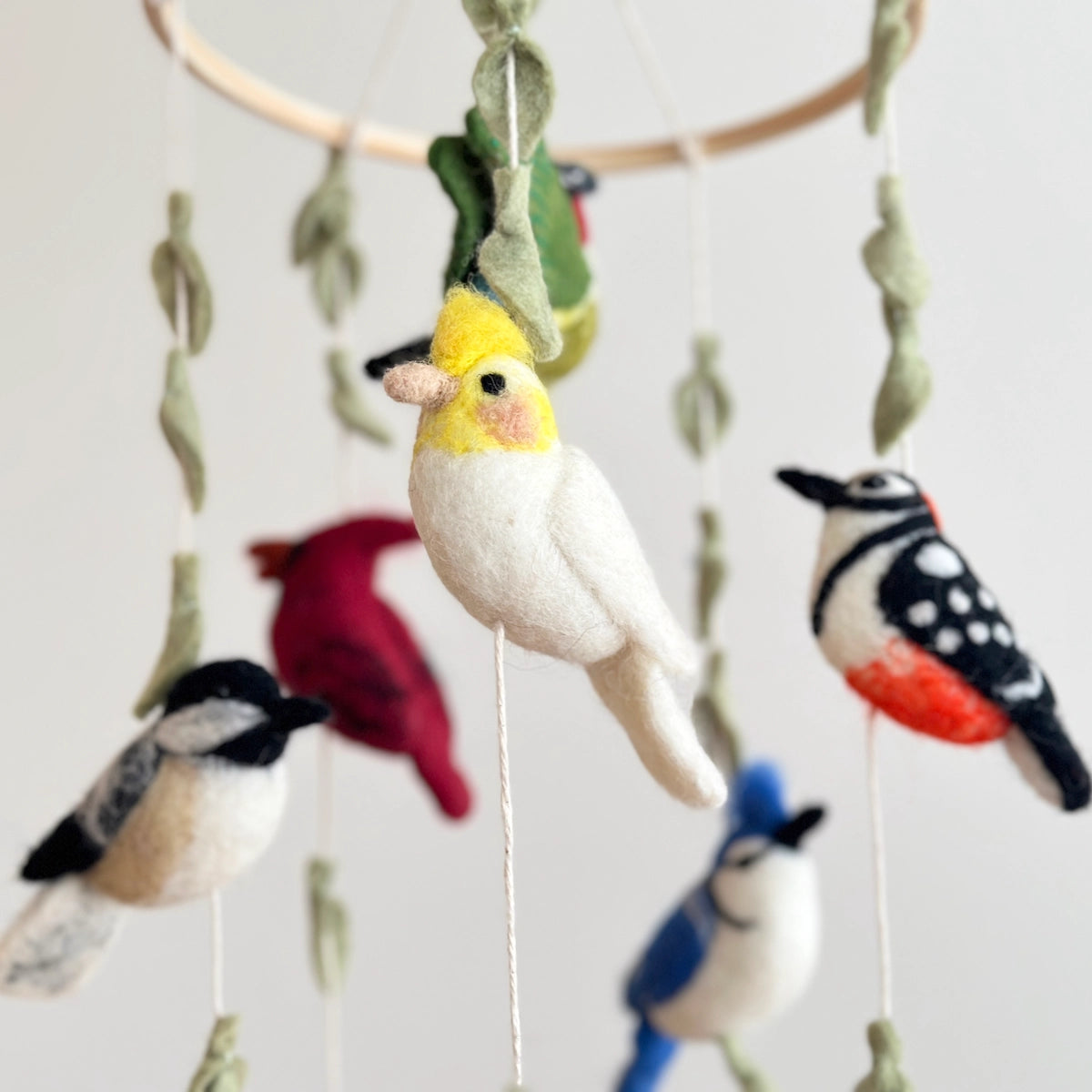 Felt bird mobile with colorful birds on a plain background