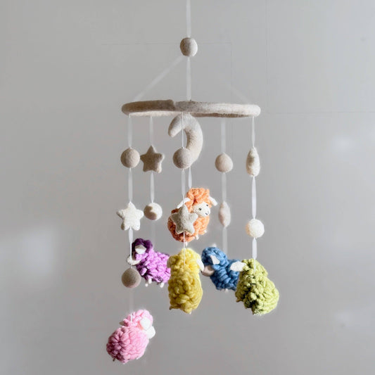 Colorful baby mobile with hanging colorful sheep against a plain background