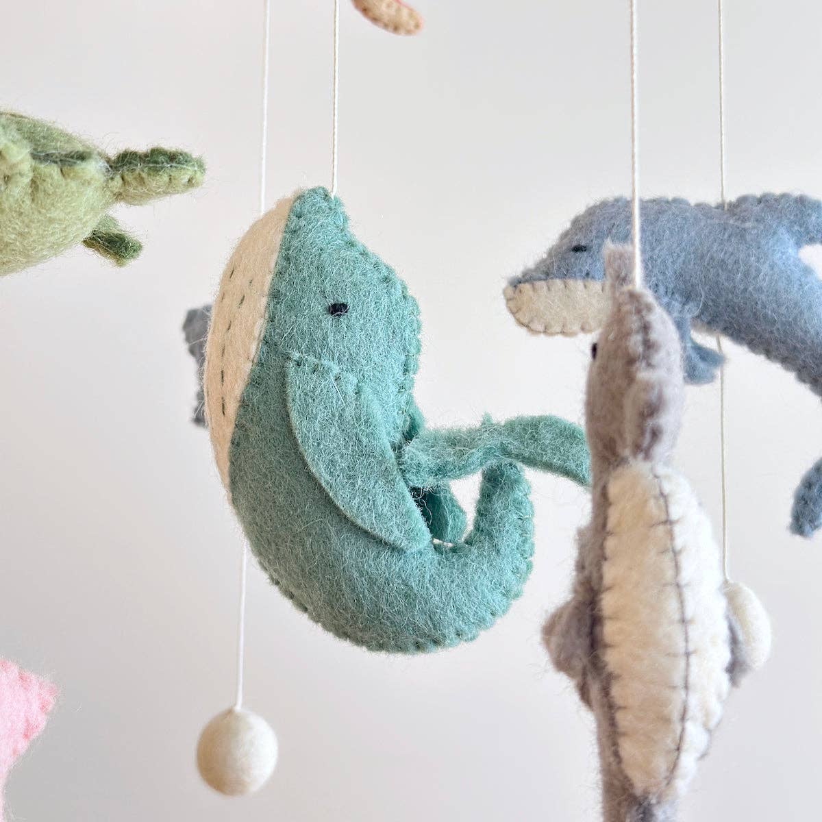 Felted sea creature mobile with dolphins and turtles on a white background