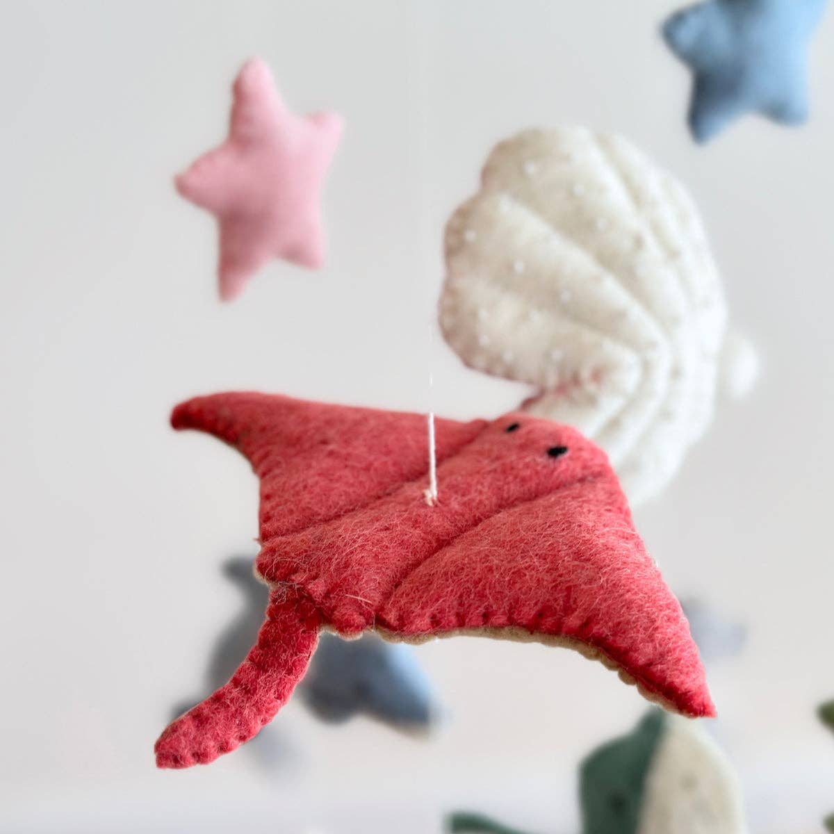 Red felt fish ornament with a blurred starfish and shell in the background