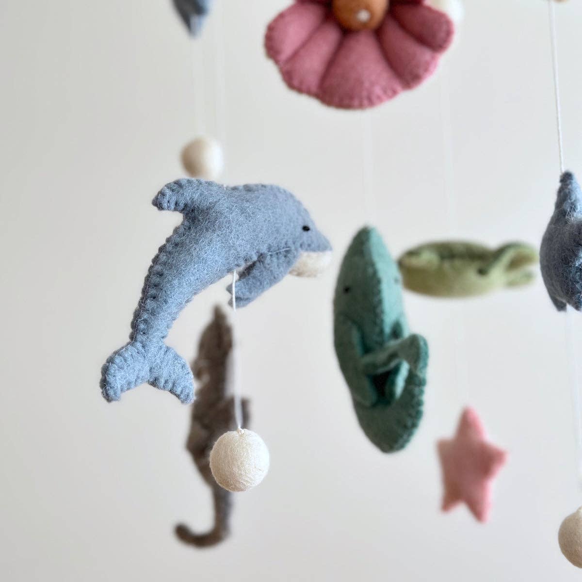 Felt sea creature mobile with dolphins, starfish, and other ocean-themed toys on a light background.