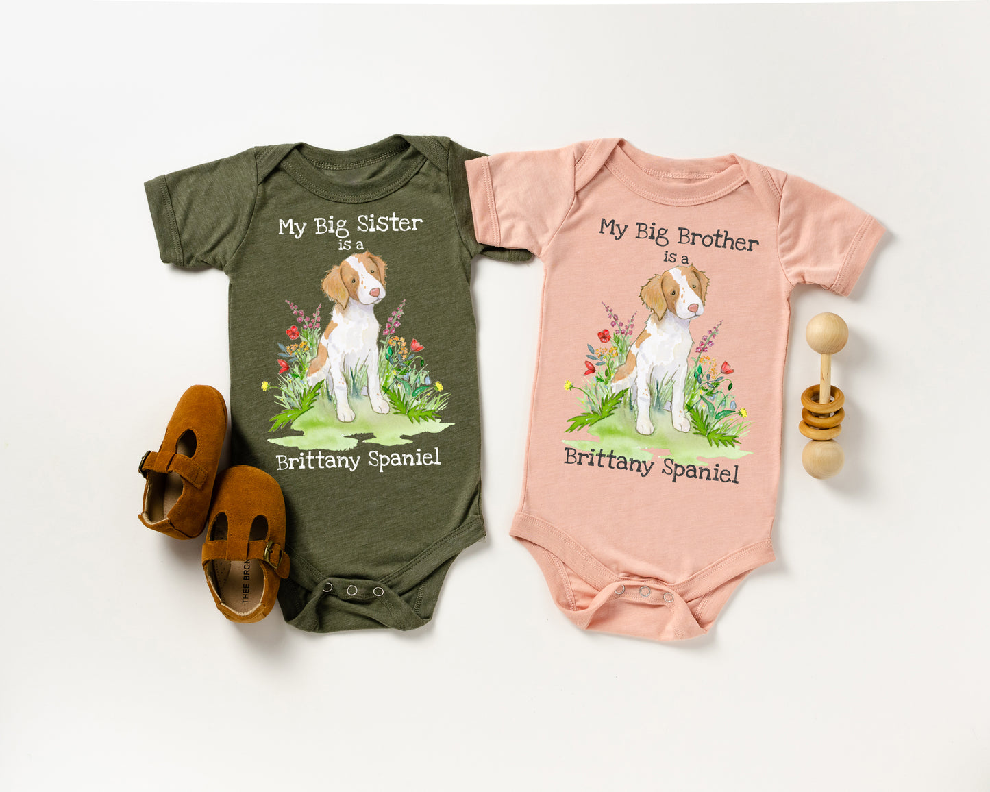 Two baby onesies with dog illustrations and text on a white background