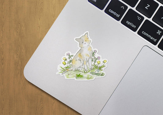 Laptop with a nature-themed sticker of a cat and flowers on a wooden surface