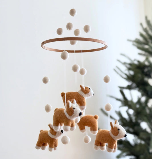 Felt corgi dog mobile with white balls on a ring against a light background