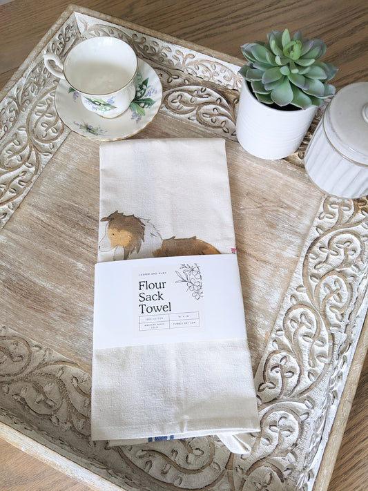 Farmhouse cotton tea towel with blue stripes and artwork of sable shetland sheepdog and flowers.