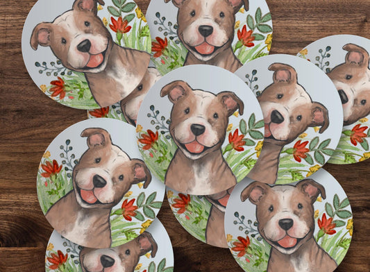 Circle sticker with a happy pitbull dog and flowers on a light blue background.