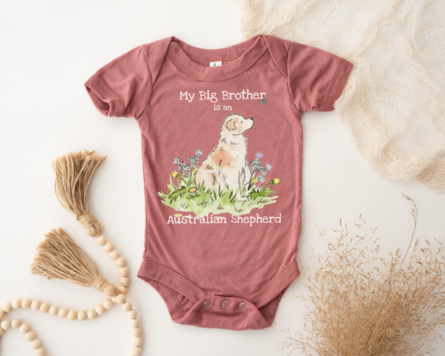 Baby onesie with 'My Big Brother is an Australian Shepherd' text and dog illustration on a light background.