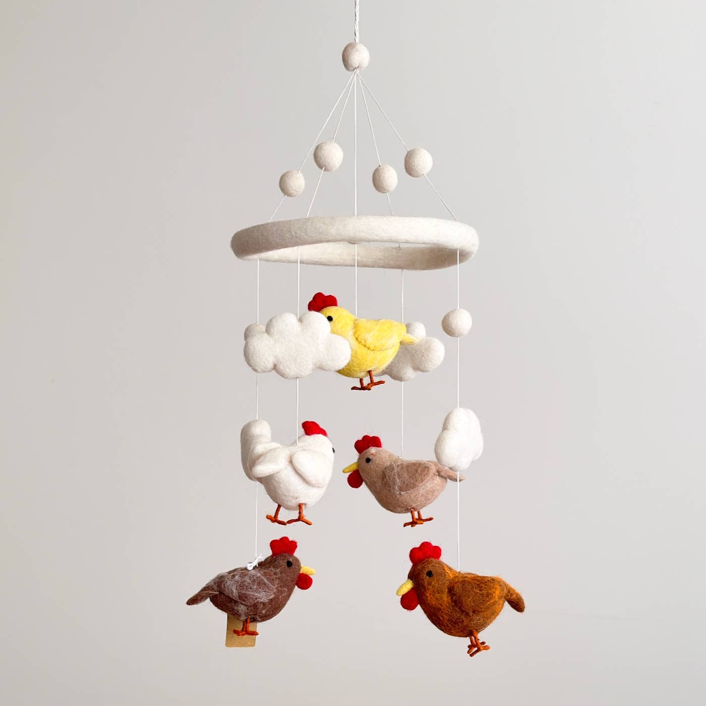 Hanging mobile with colorful chicken figures on a plain background