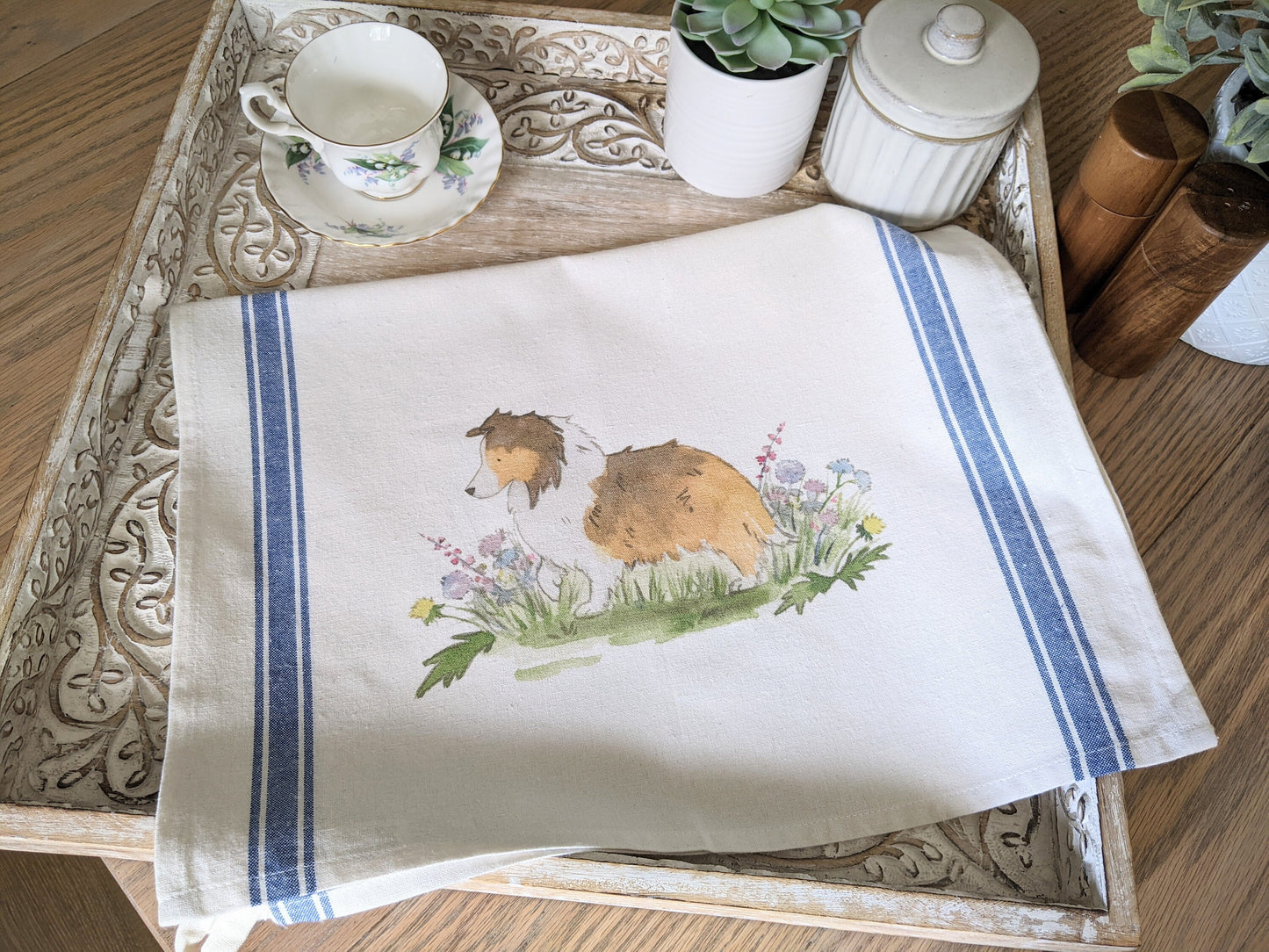Farmhouse cotton tea towel with blue stripes and artwork of sable shetland sheepdog and flowers.