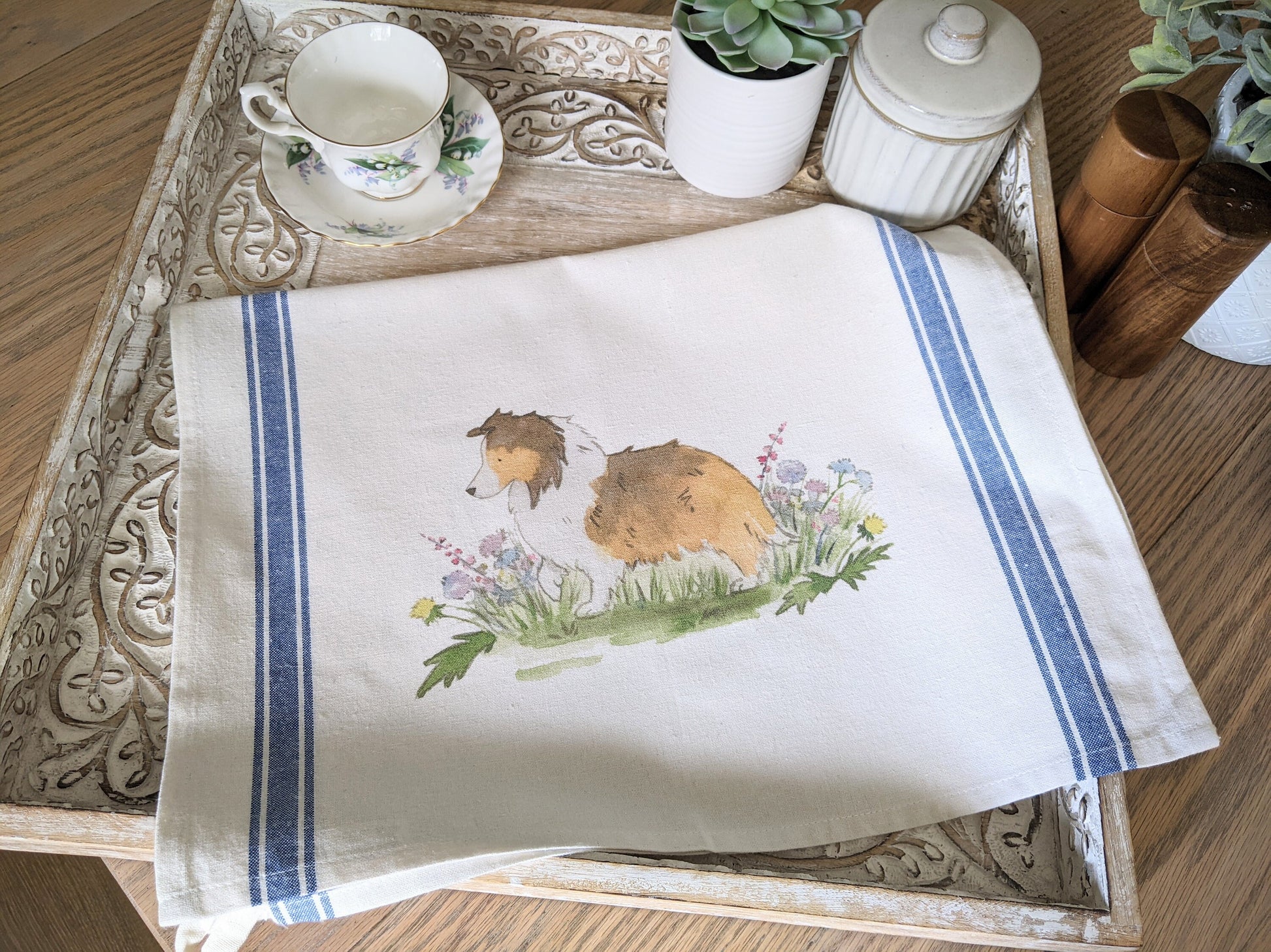 Farmhouse cotton tea towel with blue stripes and artwork of sable shetland sheepdog and flowers.