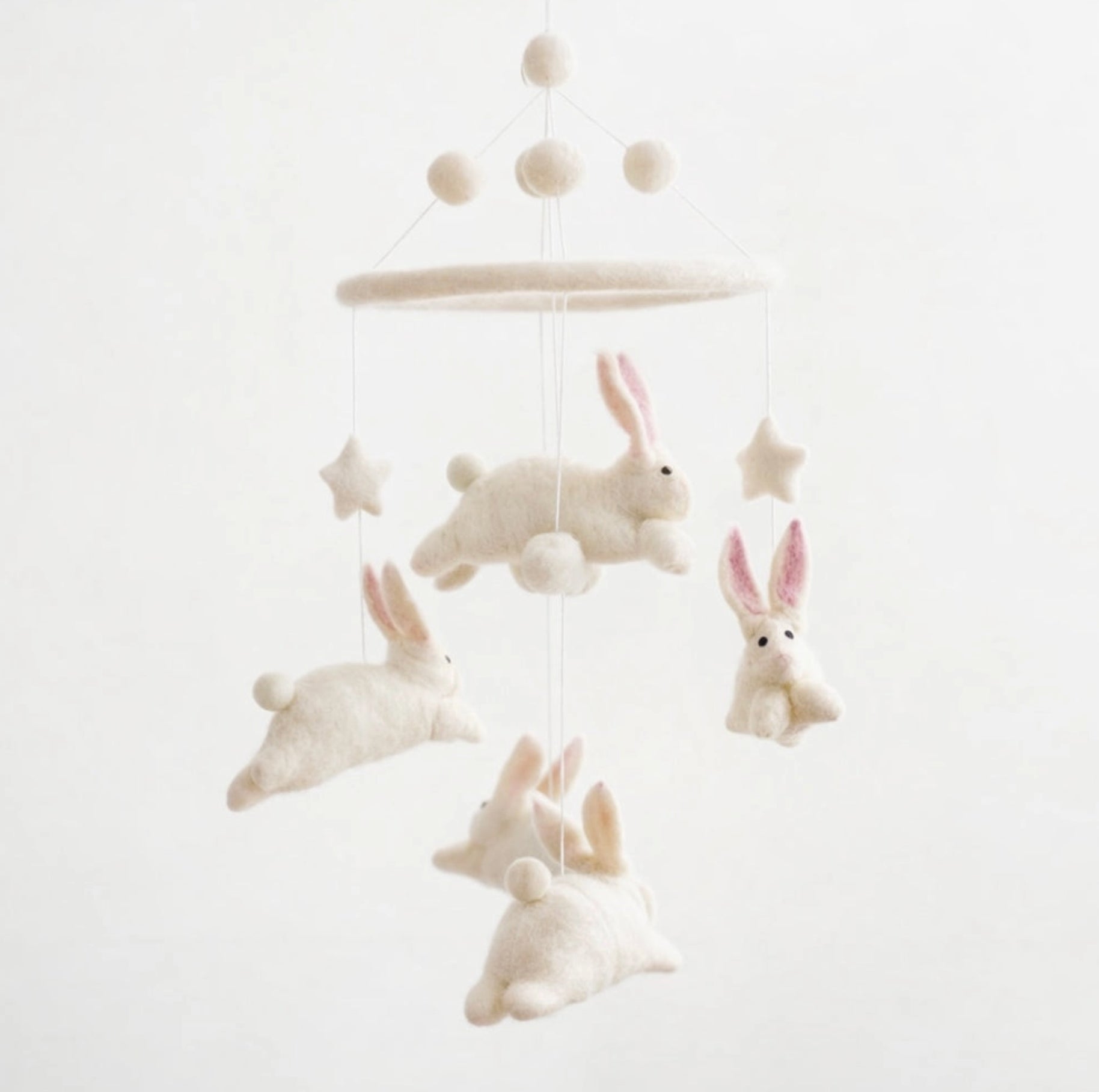 A white felt baby mobile featuring four fluffy bunny figures with pink inner ears, three star shapes, and a round hanging ring suspended against a plain white background.