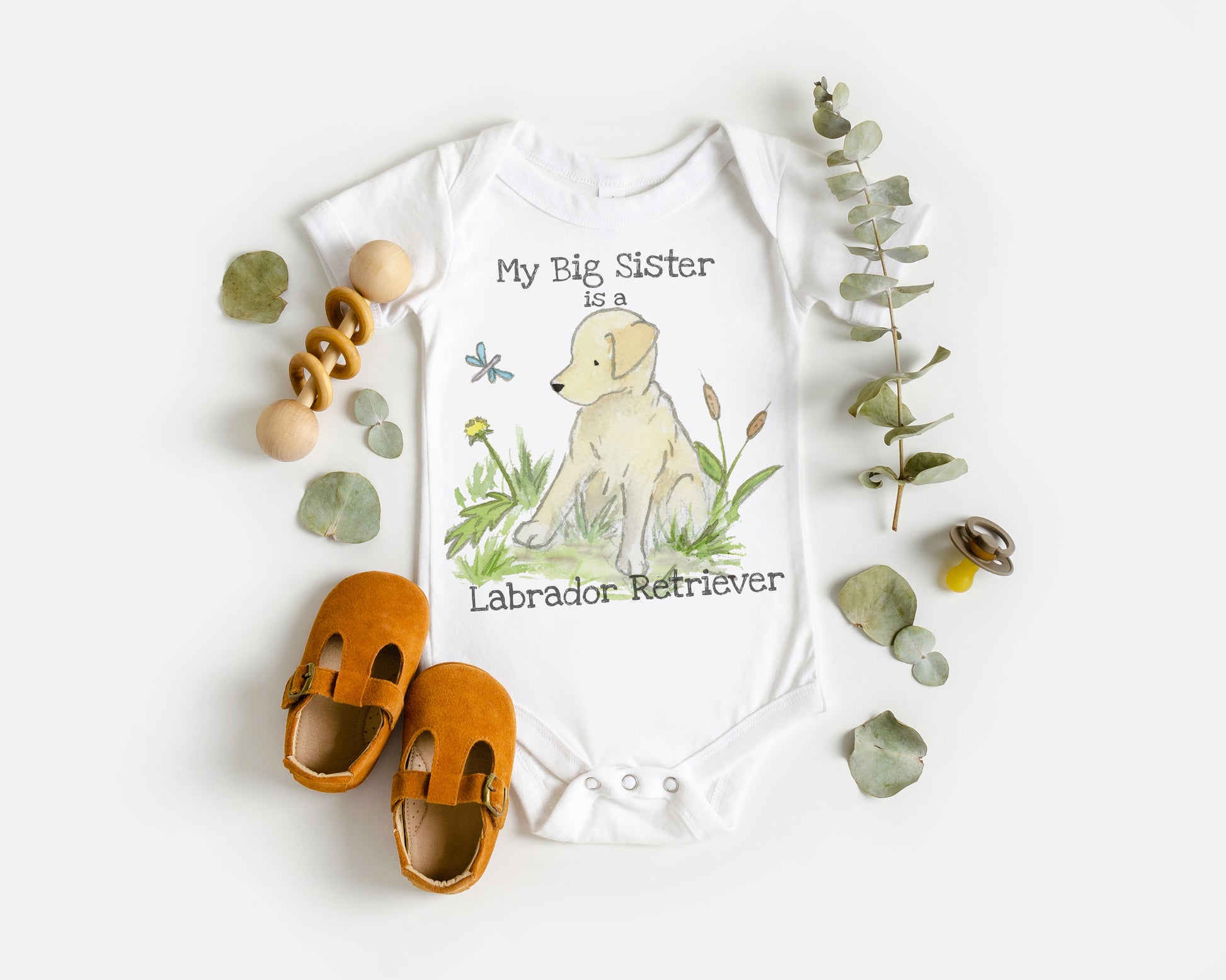Baby onesie with Labrador Retriever design and text, paired with orange shoes on a white background.