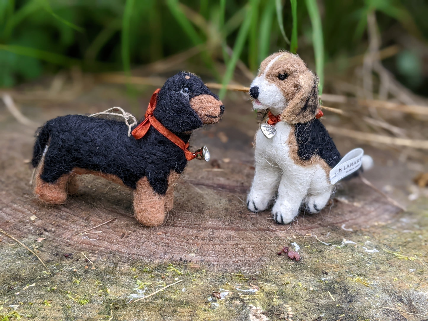 wool felted beagle and dachshund dog tiny sculptures sitting on a log