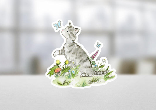 Sticker of a cat among flowers and butterflies on a white surface with a blurred background