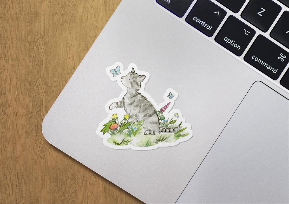 Laptop with a sticker of a cat and flowers on a wooden surface