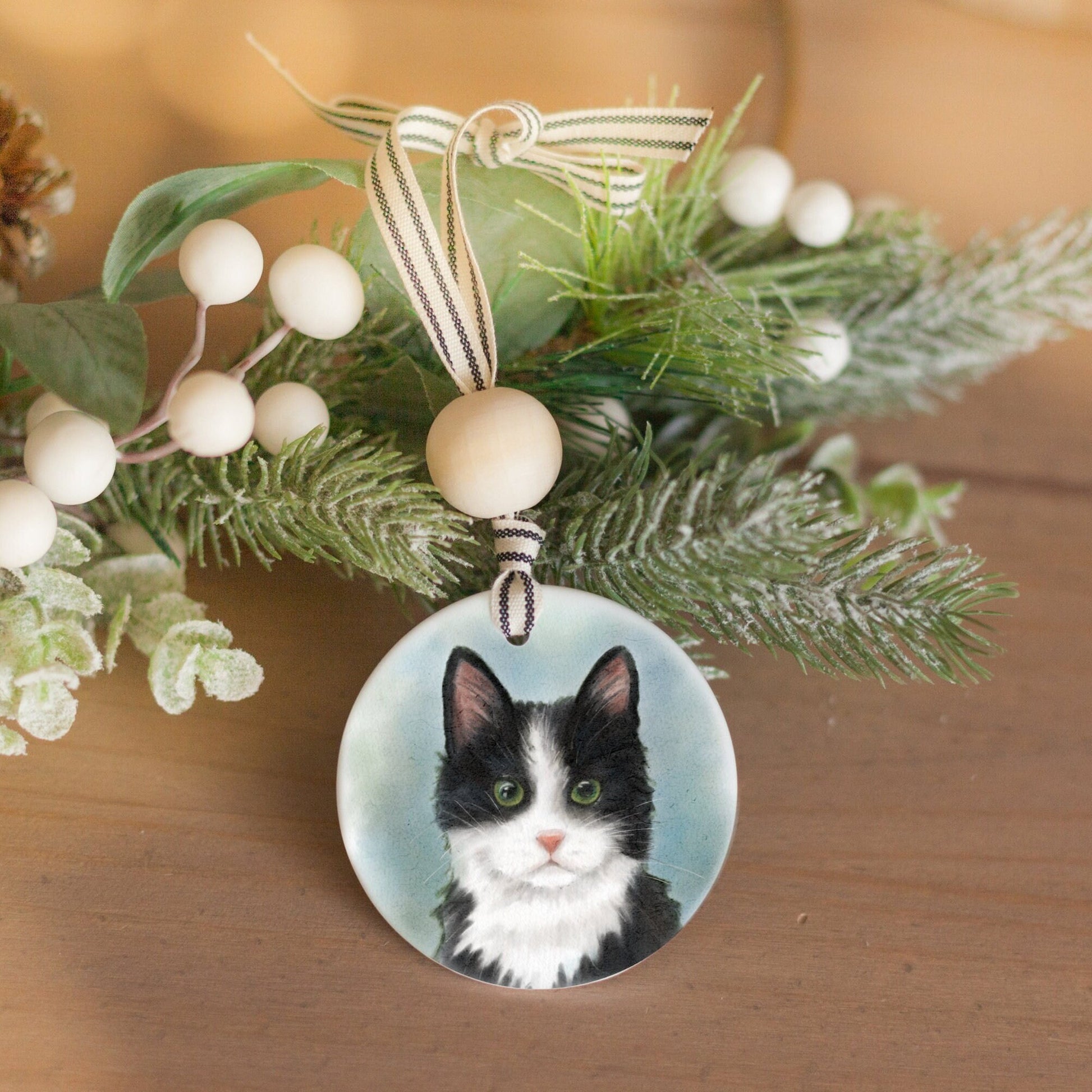 Ceramic ornament with watercolor artwork of a black and white tuxedo cat on it.