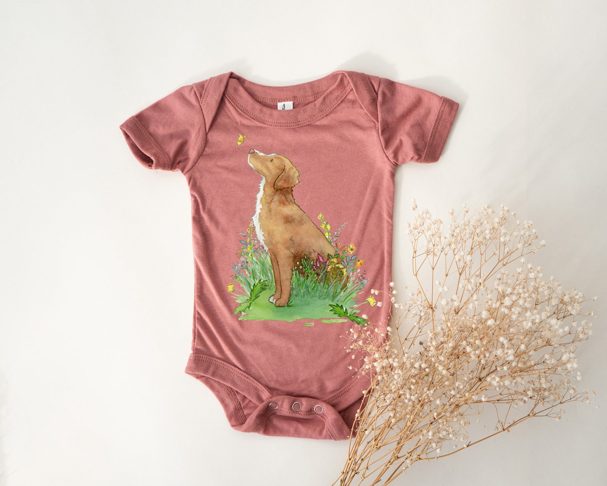 Baby one-piece bodysuit with cute artwork of a Nova Scotia Duck Tolling Retriever looking at a butterfly on it.