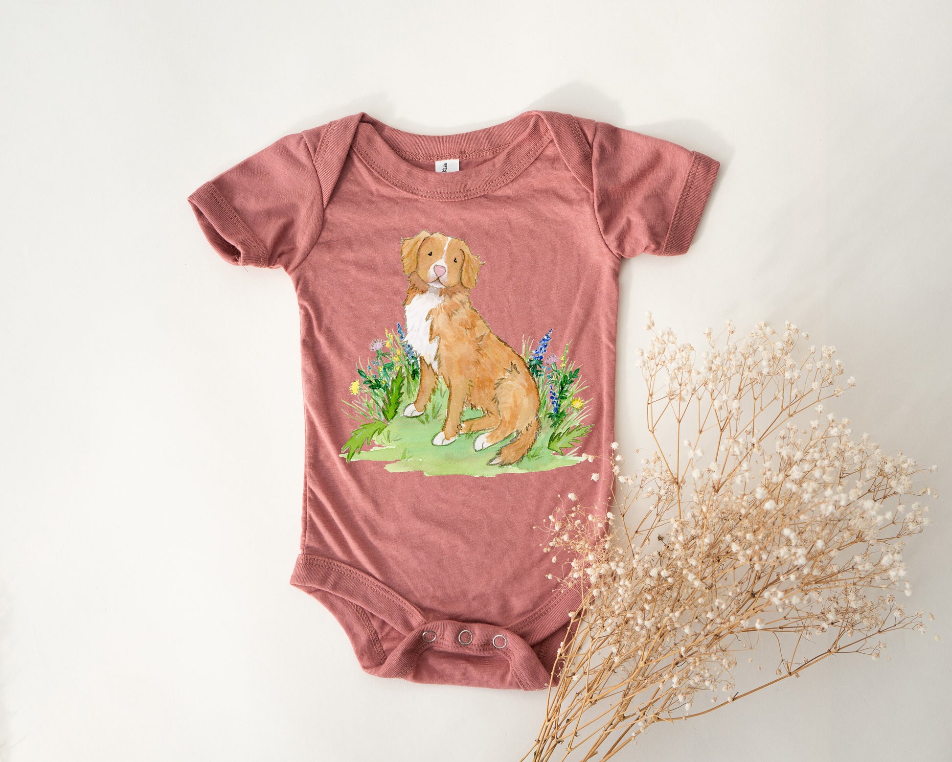 Baby one-piece bodysuit with cute artwork of a Nova Scotia Duck Tolling Retriever looking at a butterfly on it.