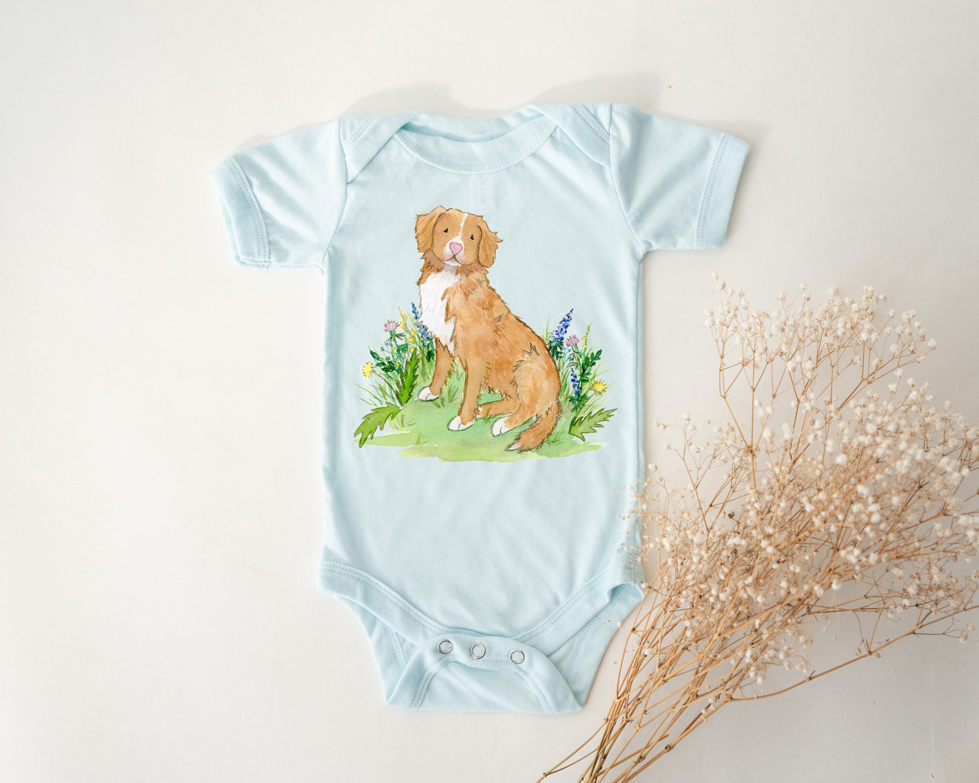 Baby one-piece bodysuit with cute artwork of a Nova Scotia Duck Tolling Retriever looking at a butterfly on it.