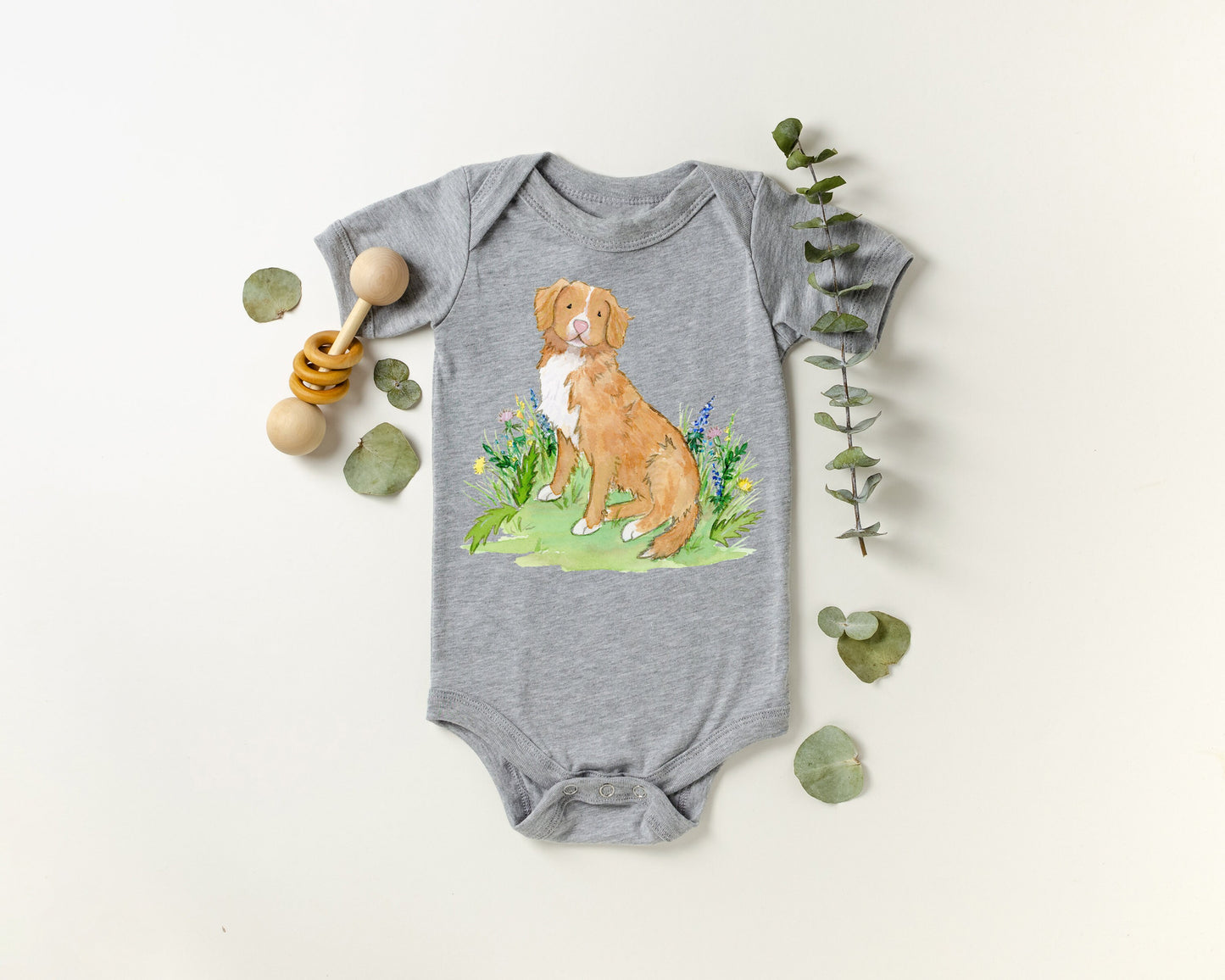 Baby one-piece bodysuit with cute artwork of a Nova Scotia Duck Tolling Retriever looking at a butterfly on it.