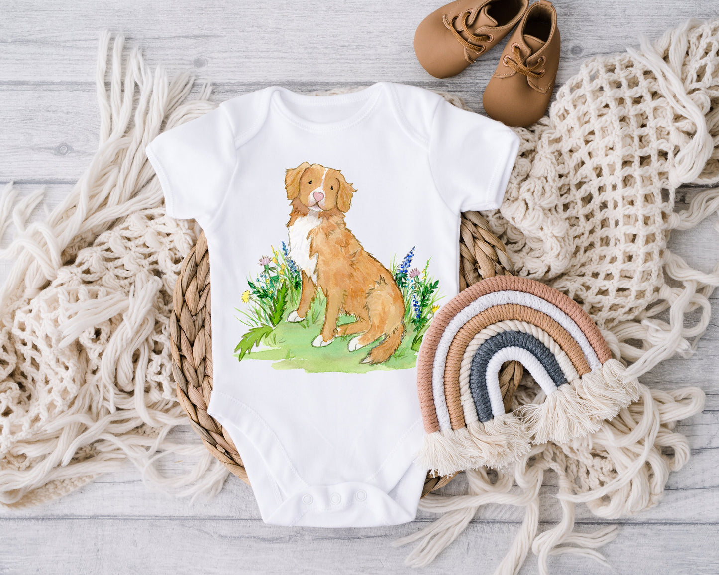 Baby one-piece bodysuit with cute artwork of a Nova Scotia Duck Tolling Retriever looking at a butterfly on it.