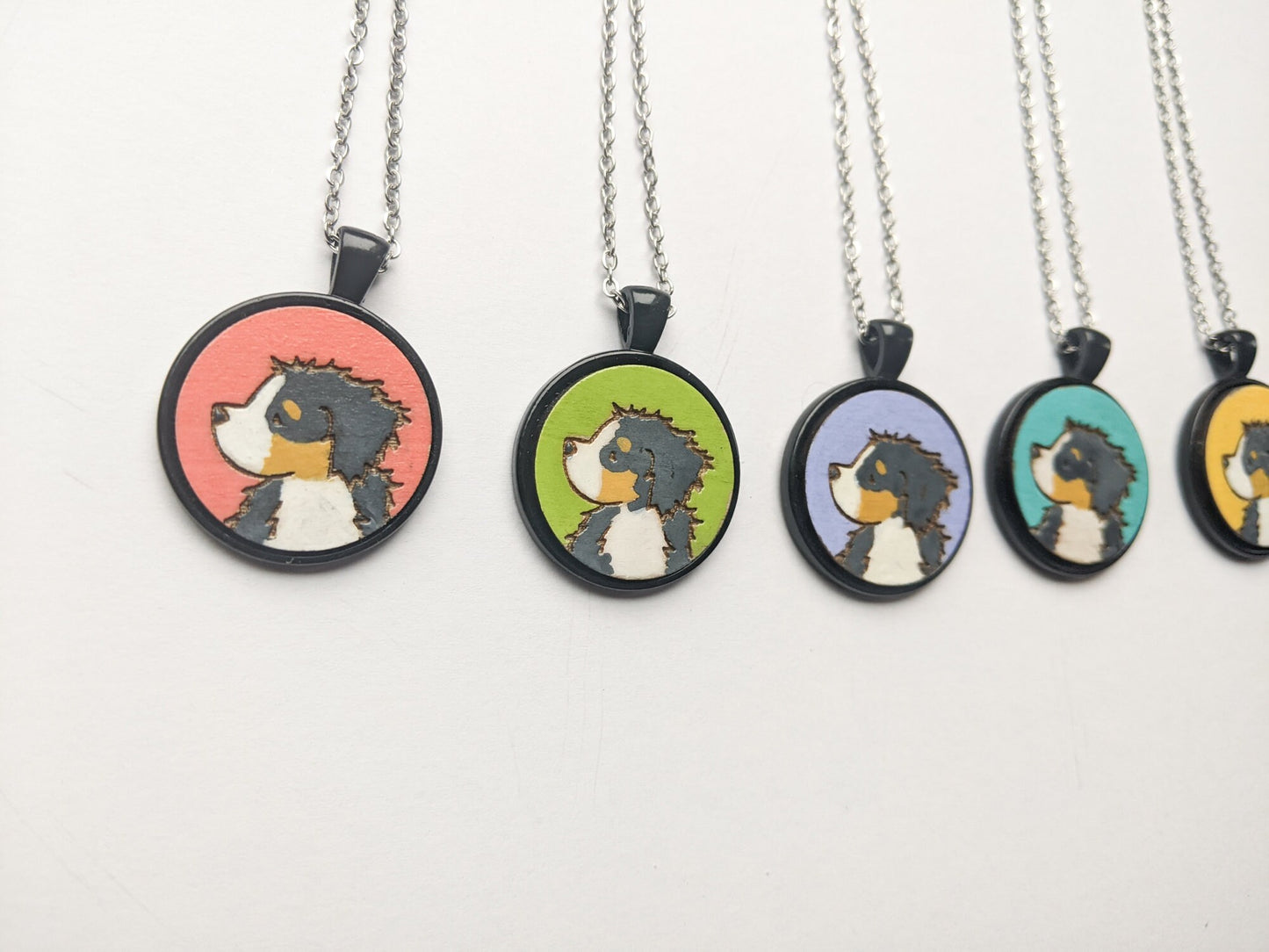 Hand painted Bernese Mountain Dog necklaces with a variety of bright background colors