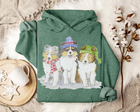 Hooded sweatshirt with three sheltie puppies wearing winter hats and scarves.