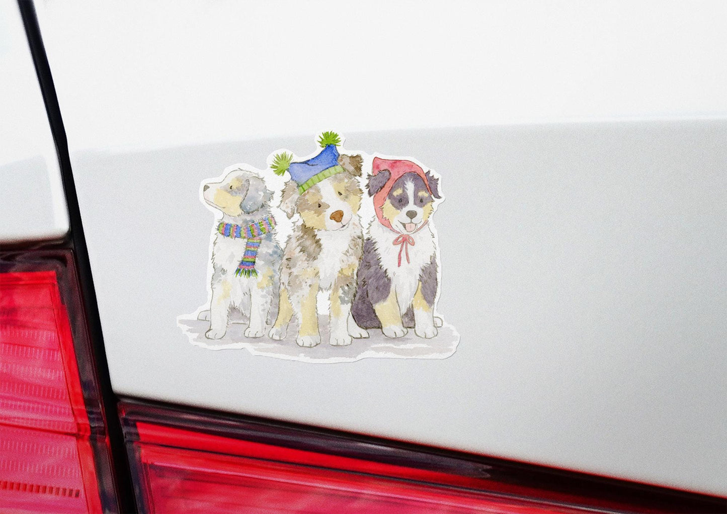 vinyl stickers with Australian Shepherd pups wearing festive hats and scarves on a car