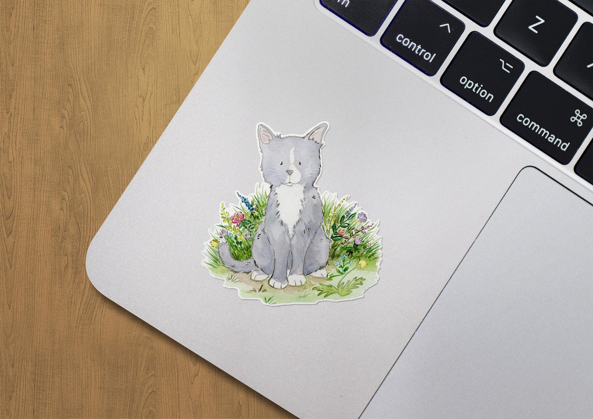 Gray and white kitten sitting in a patch of colorful flowers sticker.