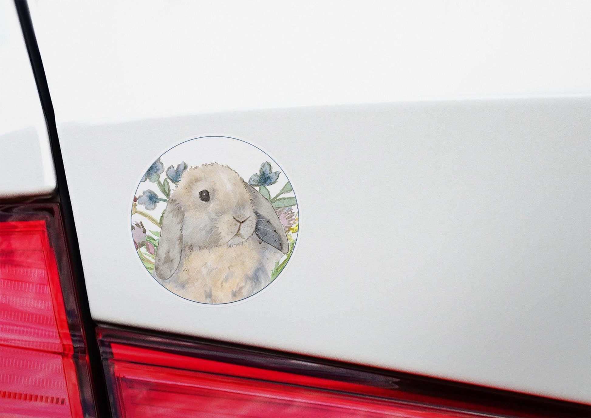 Circle sticker with a blue tort holland lop bunny and flowers on it.
