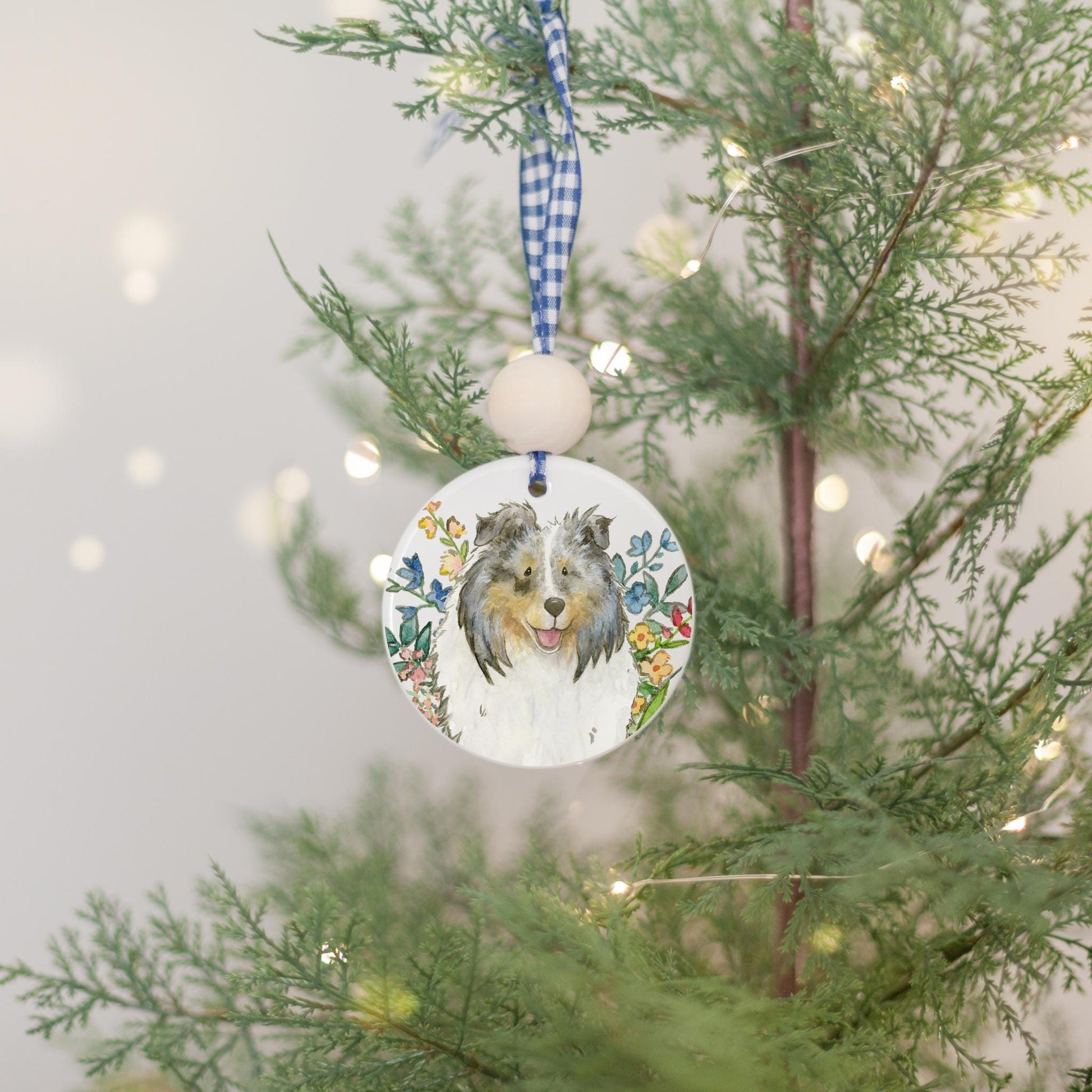 Blue merle sheltie and colorful flowers on a ceramic ornament.