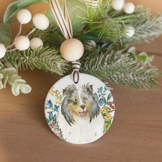 Blue merle sheltie and colorful flowers on a ceramic ornament.