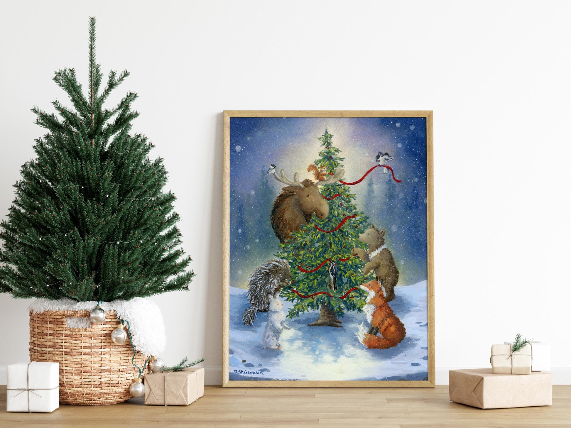 Framed art print with a cozy winter scene featuring Alaskan animals decorating a Christmas tree.  The painting is surrounded by gifts and a small Christmas tree.