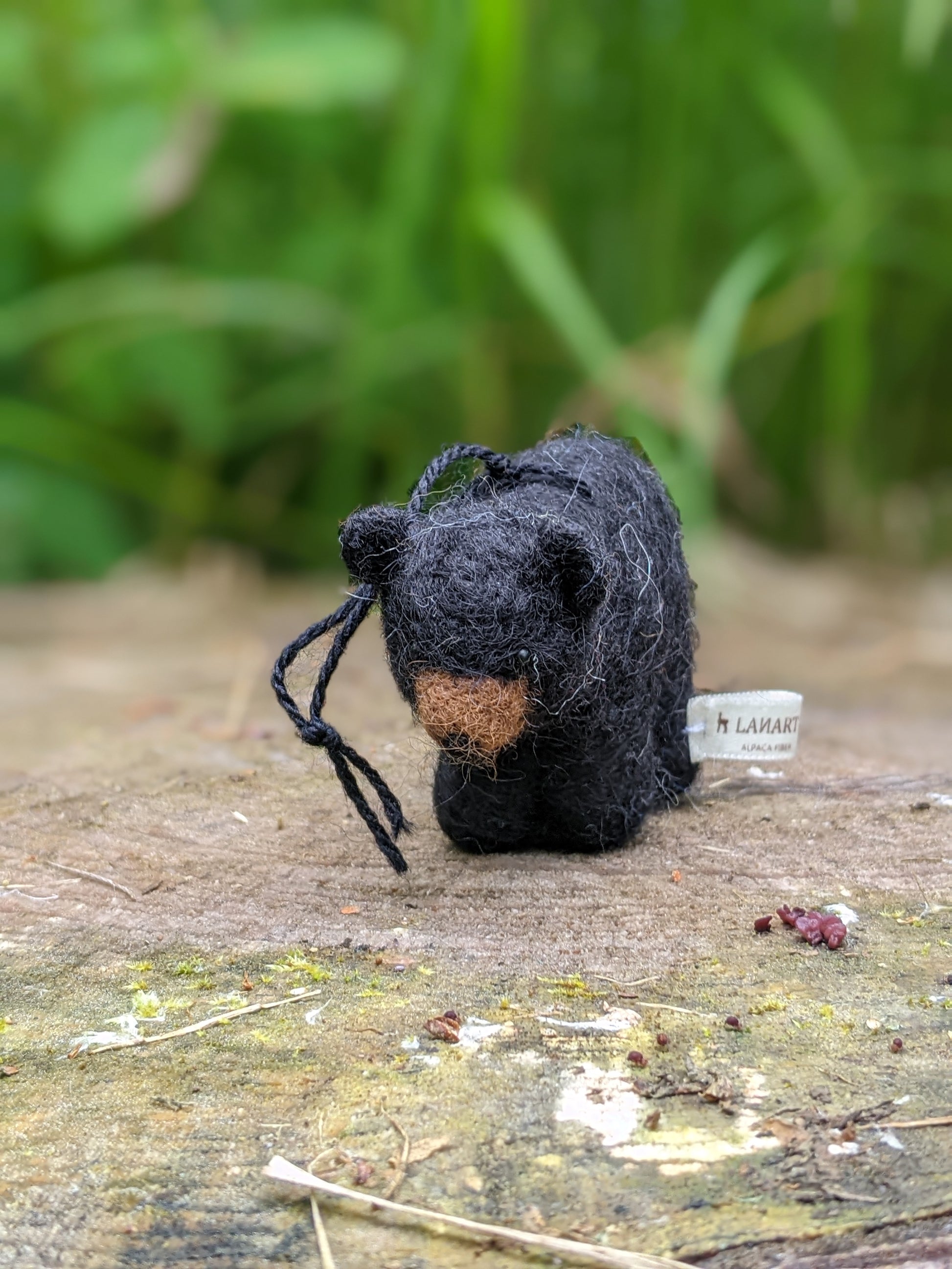 needle felted wool black bear cub sculpture sitting on a log