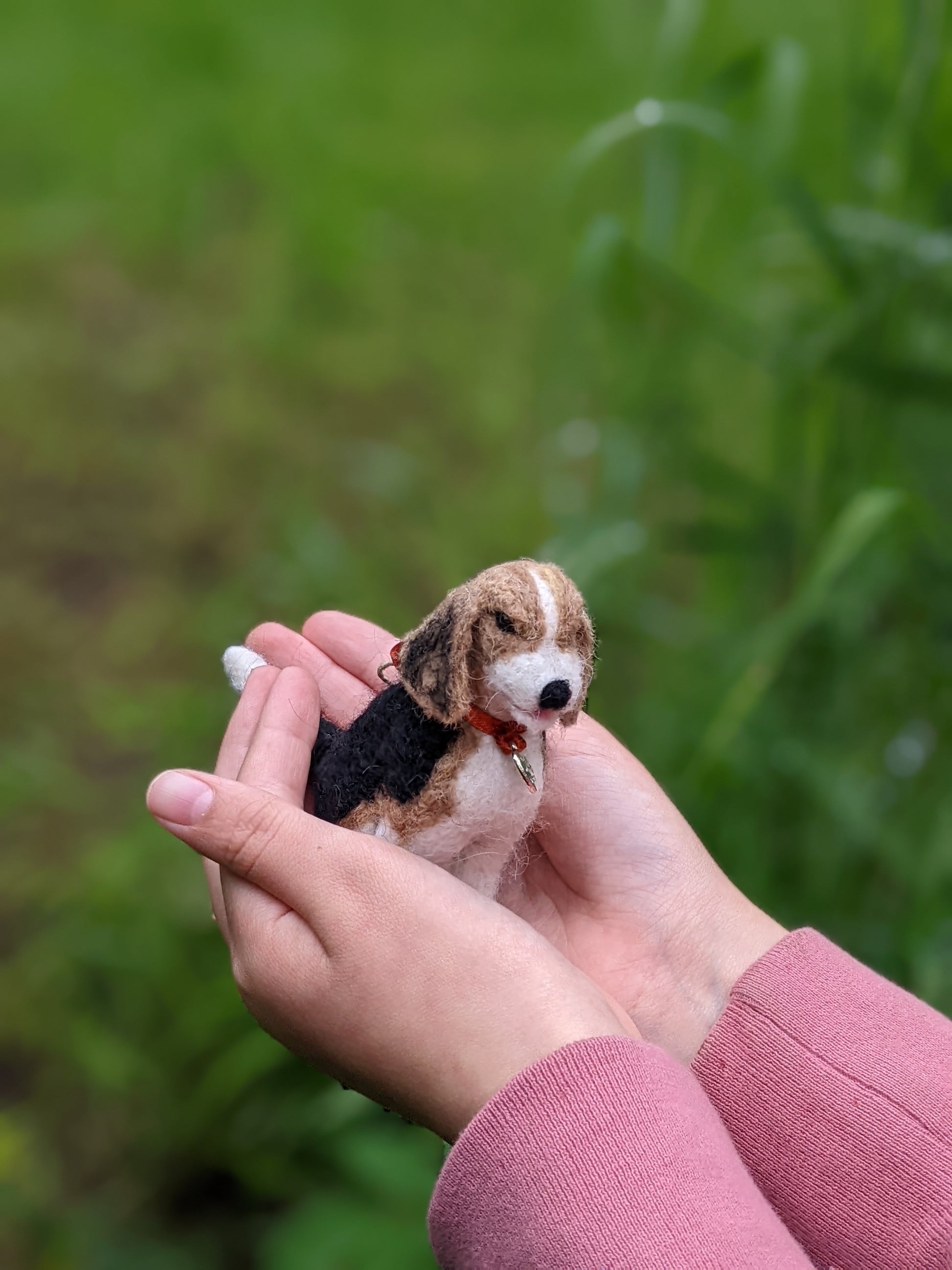 cute needle felted wool beagle dog sculpture held in childs hands