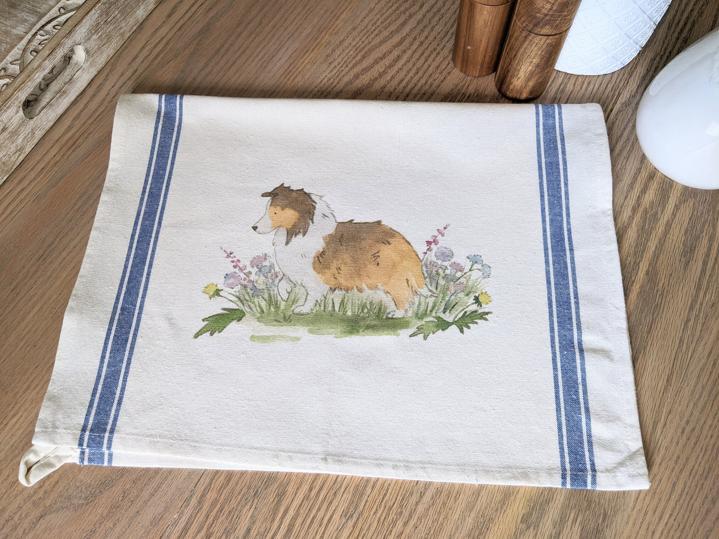 Farmhouse cotton tea towel with blue stripes and artwork of sable shetland sheepdog and flowers.