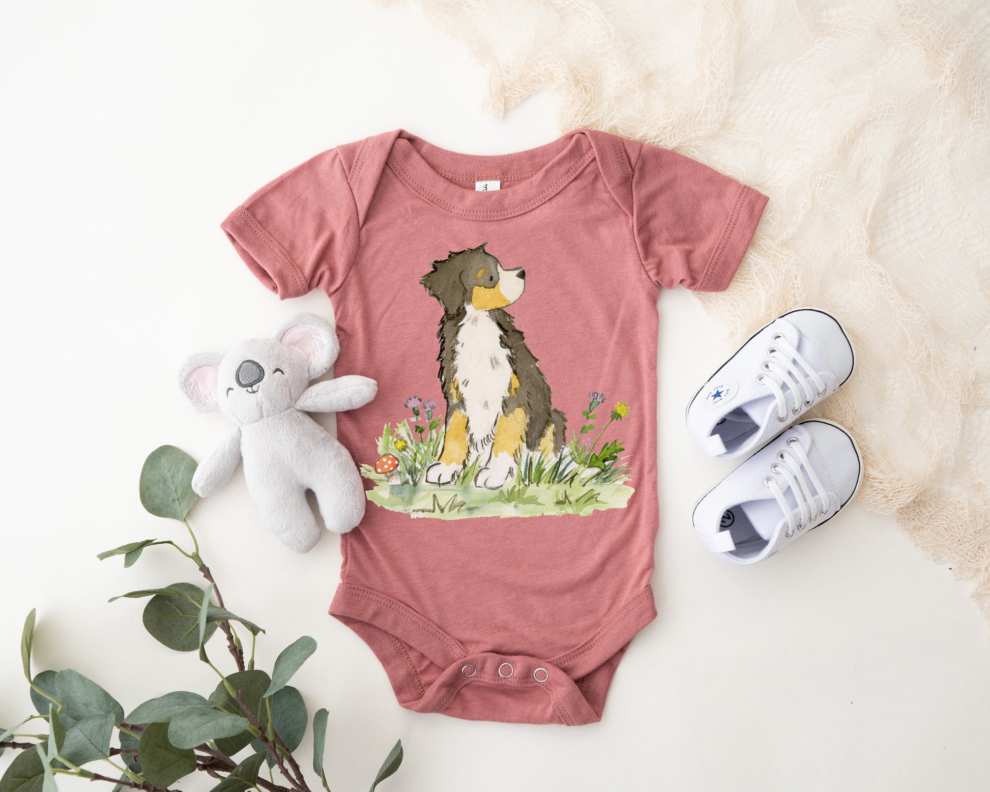 Peach colored infant bodysuit with artwork of a cute Bernese Mountain Dog on it.