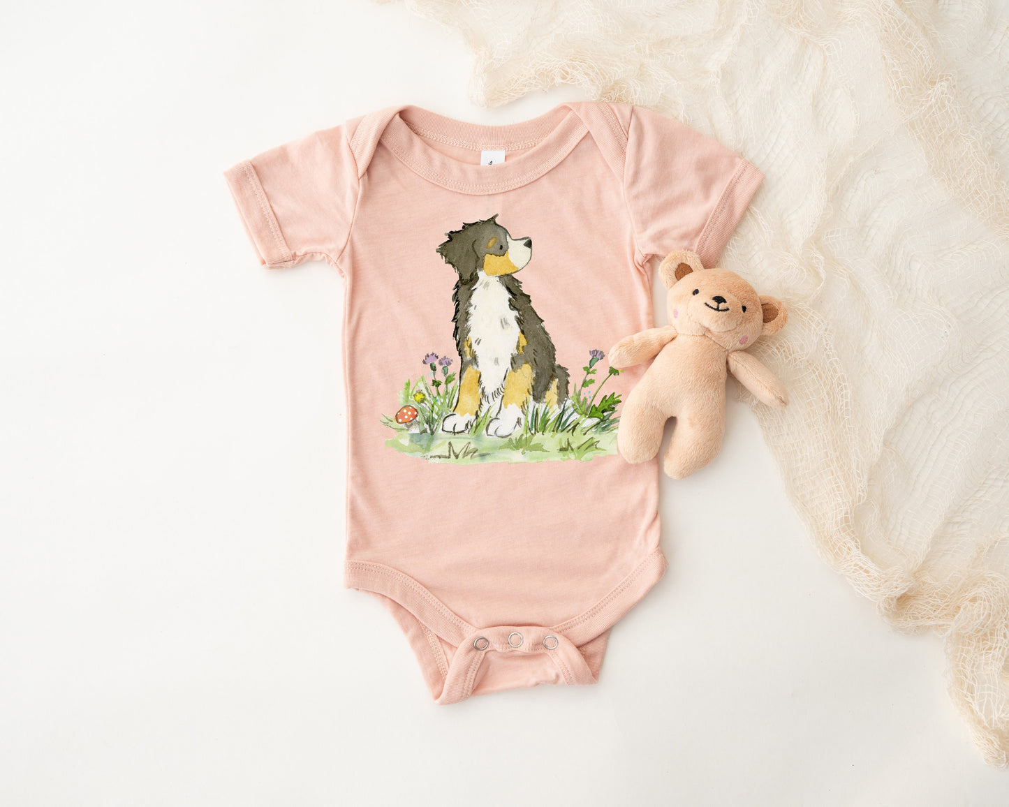 Peach colored infant bodysuit with artwork of a cute Bernese Mountain Dog on it.