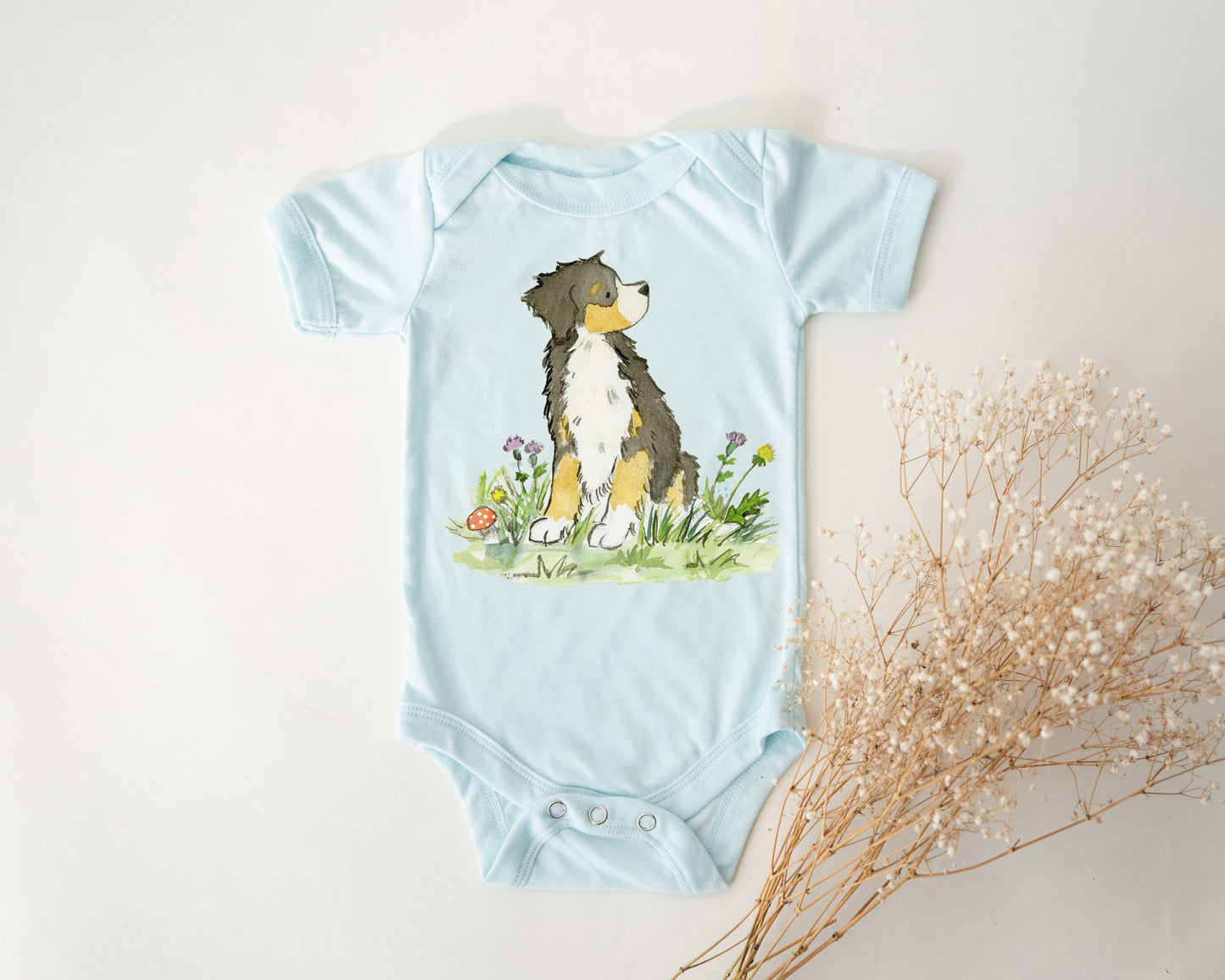 Light Blue colored infant bodysuit with artwork of a cute Bernese Mountain Dog on it.