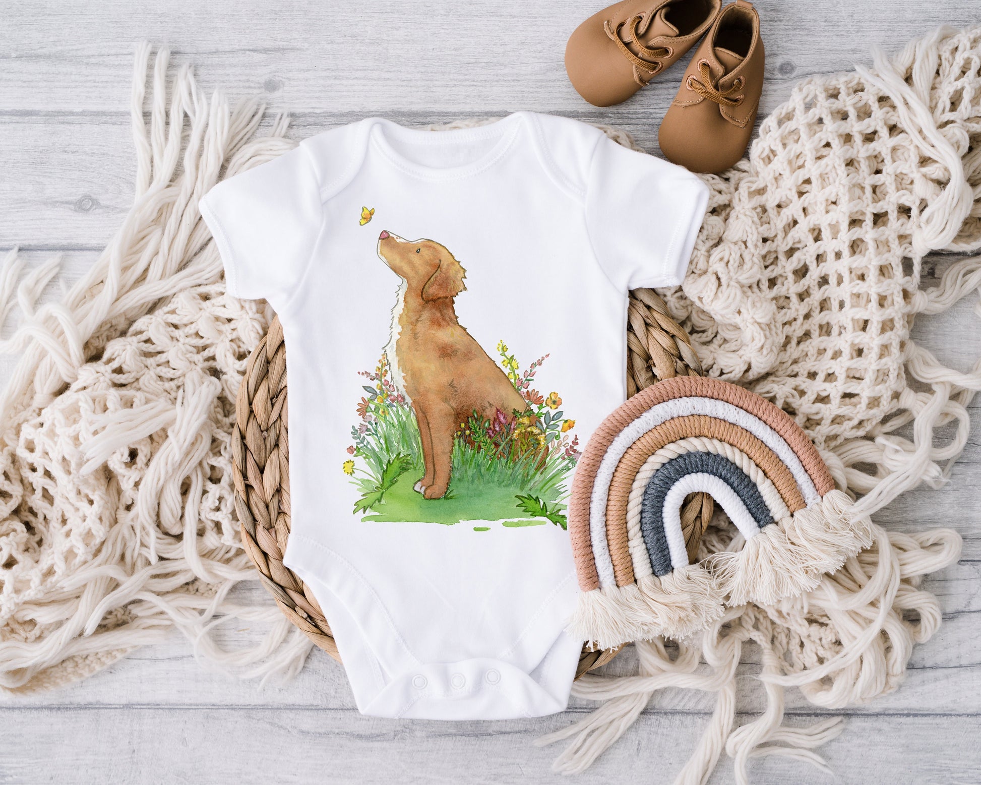 Baby one-piece bodysuit with cute artwork of a Nova Scotia Duck Tolling Retriever looking at a butterfly on it.